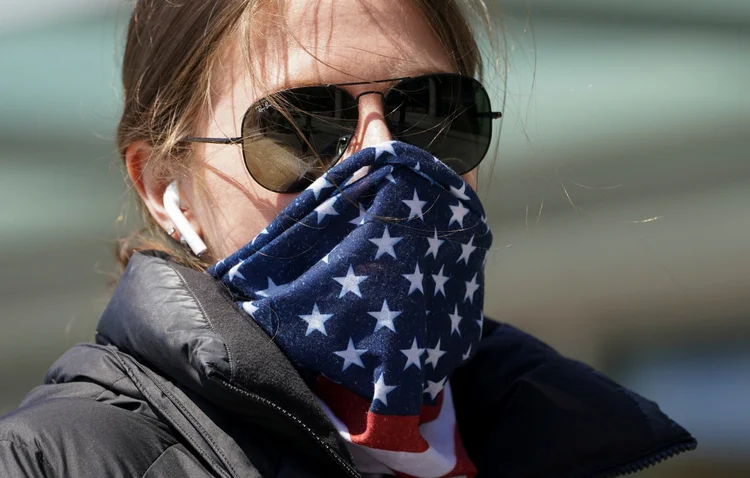 Mulher com bandeira americana: óbitos nos EUA atingiram o pico em abril, quando o país registrou cerca de 2 mil mortes por dia (Kevin Lamarque/Reuters)