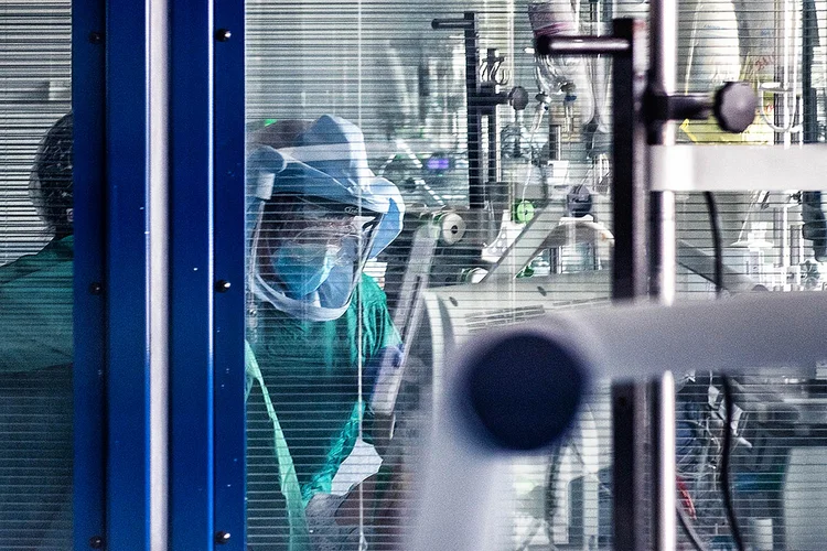 Um profissional de saúde usando roupas protetoras atende a uma paciente numa UTI  de hospital (Andreas Solaro/AFP)