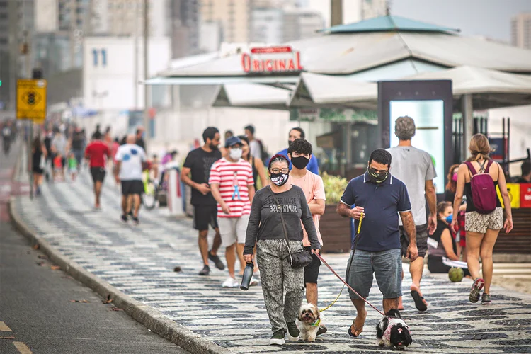 Pedestres com máscaras protetoras andam na calçada da praia do Leblon, em 6 de junho de 2020, no Rio de Janeiro (Andre Coelho/Getty Images)