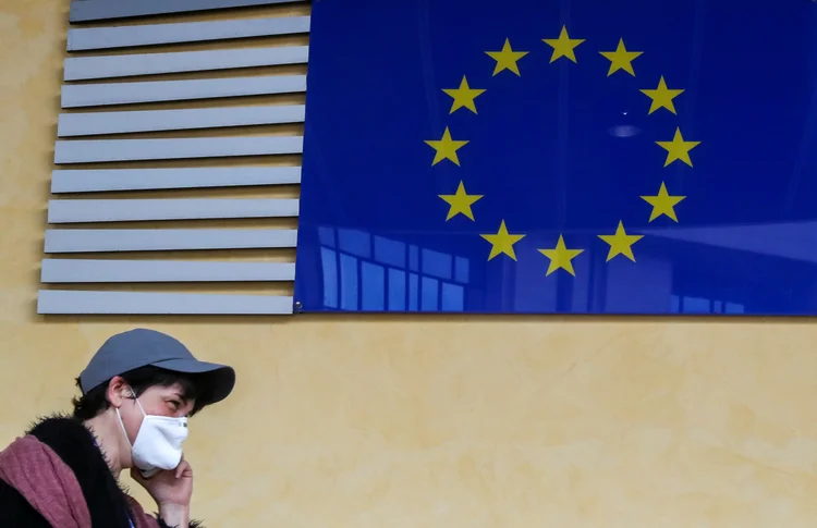 Mulher usando máscara de proteção passa pelo símbolo da União Europeia, 5 de junho de 2020.   (Yves Herman/Reuters)