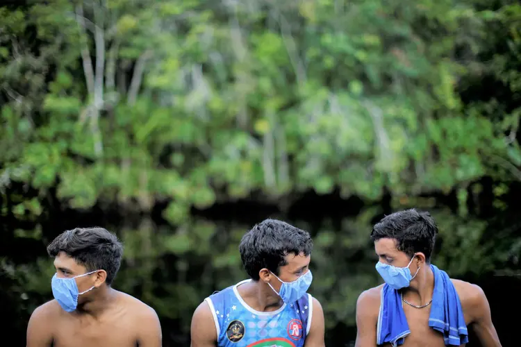 Aldeia no Pará: Indígenas com máscaras de proteção contra Covid-19 conversam enquanto agentes de saúde checam moradores  (Ueslei Marcelino/Reuters)