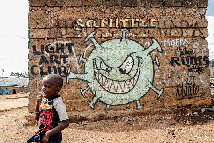 Garoto passa em frente a um grafite que promove a luta contra a covid-19 nas favelas de Mathare, em Nairobi, Quênia, 22 de maio de 2020.  (Baz Ratner/Reuters)
