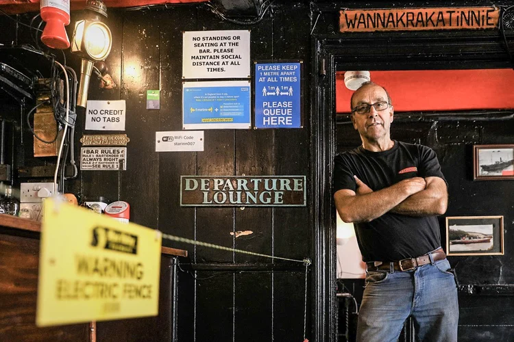 Johnny McFadden, dono do pub Star Inn, em St Just, na Inglaterra, posa para foto ao lado de cerca elétrica instalada (Tom Nicholson/Reuters)
