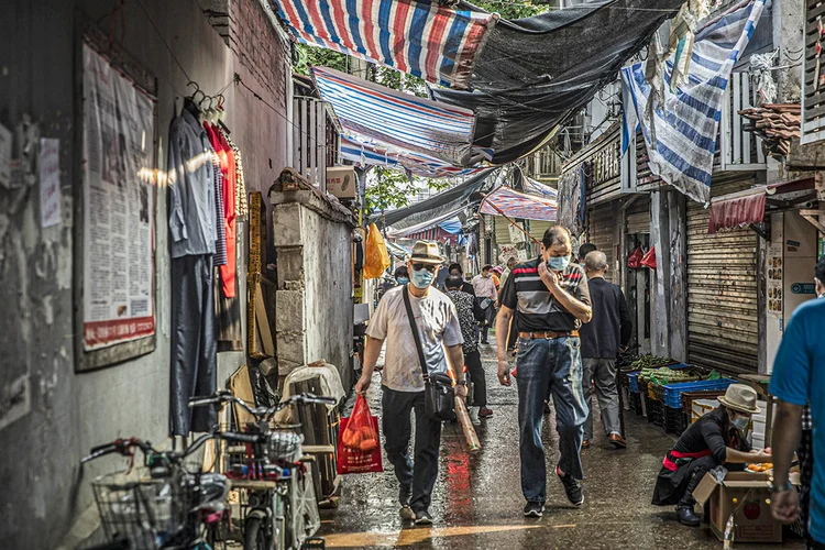 Pedestres usando máscaras protetoras passam por lojas em Wuhan, na China, 1º de maio de 2020.  (Qilai Shen/Bloomberg)