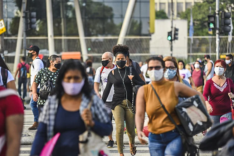 Pedestres usando máscara de proteção contra covid-19 atravessam uma rua no Rio de Janeiro (Fabio Teixeira/Anadolu Agency via/Getty Images)