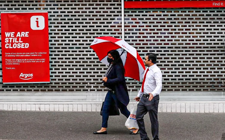 Pessoas passam por uma loja fechada durante o bloqueio em Leicester, Inglaterra, em 1º de julho de 2020 (Darren Staples/Getty Images)