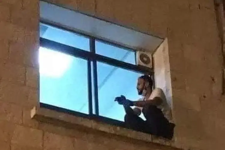 JJihad Al-Suwaiti: jovem palestino acompanhando o tratamento da mãe contra a covid-19 pela janela de hospital na Cisjordânia (Twitter/Mohamad Safa/Reprodução)