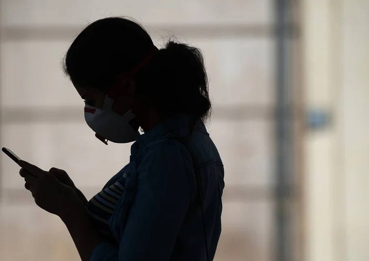 Pessoa de máscara e celular: das 69 universidade federais do Brasil, 25 universidades estão com aulas remotas (Jesus Merida/Getty Images)