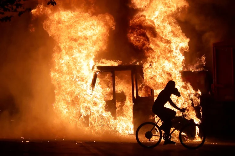 Um homem em uma bicicleta passa por um caminhão em chamas fora do tribunal do condado de Kenosha: (Mike De Sisti/Milwaukee Journal Sentinel via USA TODAY/Reuters)