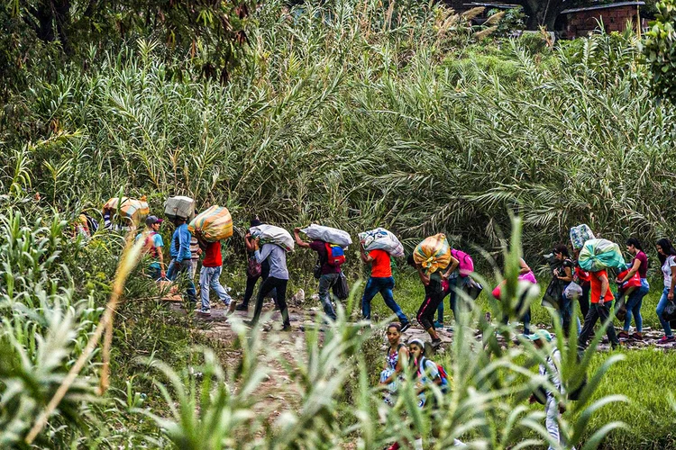 Venezuelanos carregam pertences perto da fronteira da Venezuela com a Colômbia.  (Federico Rios/Bloomberg)