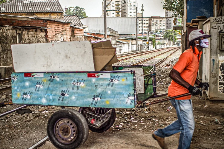 Homem usando máscara protetora puxa carrinho pelos trilhos de trem na Favela do Moinho, em São Paulo, Brasil, na quinta-feira, 25 de junho de 2020. (Marcelo Rochas/Bloomberg)