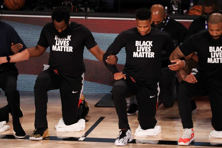 Protesto na NBA durante hino: jogadores do Houston Rockets e do Dallas Mavericks se ajoelham de braços dados; outras ligas americanas não fizeram o mesmo (Mike Ehrmann/Getty Images)