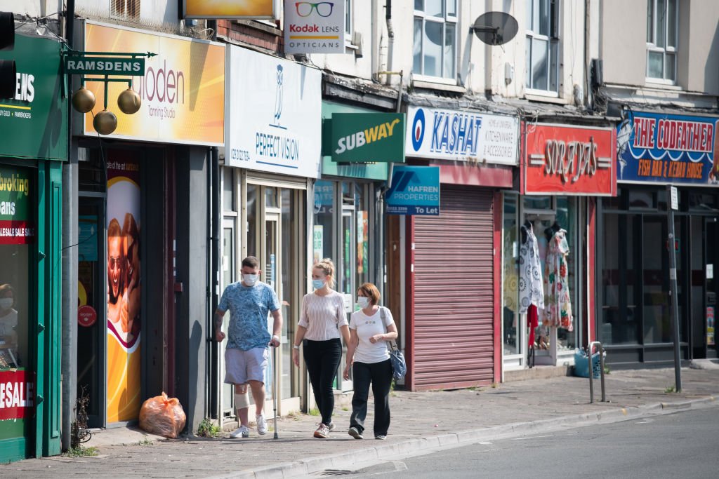 Pessoas de máscaras de proteção caminham pela Cowbridge Road East, em 12 de agosto de 2020, Cardiff, País de Gales.