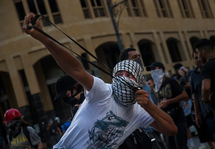 Libanês usa estilingue para jogar pedra na polícia durante os protestos em Beirute (Daniel Carde/Getty Images)