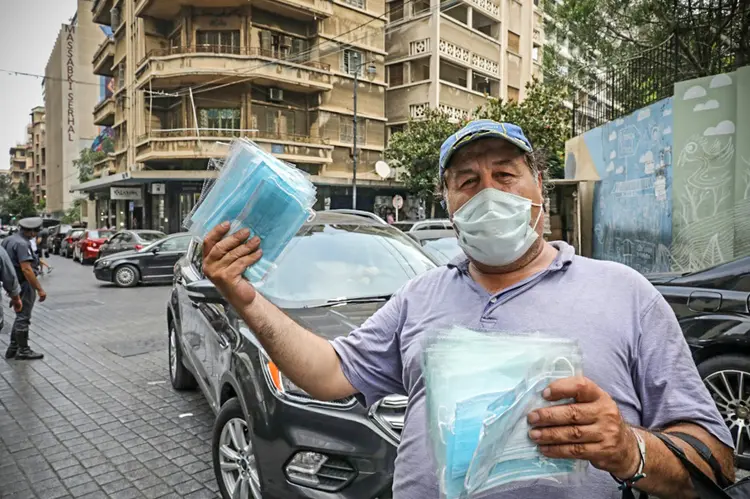 Homem distribui máscaras no Líbano: a explosão no porto matou mais do que o coronavírus, mas hospitais lotados preocupam (AFP/AFP Photo)
