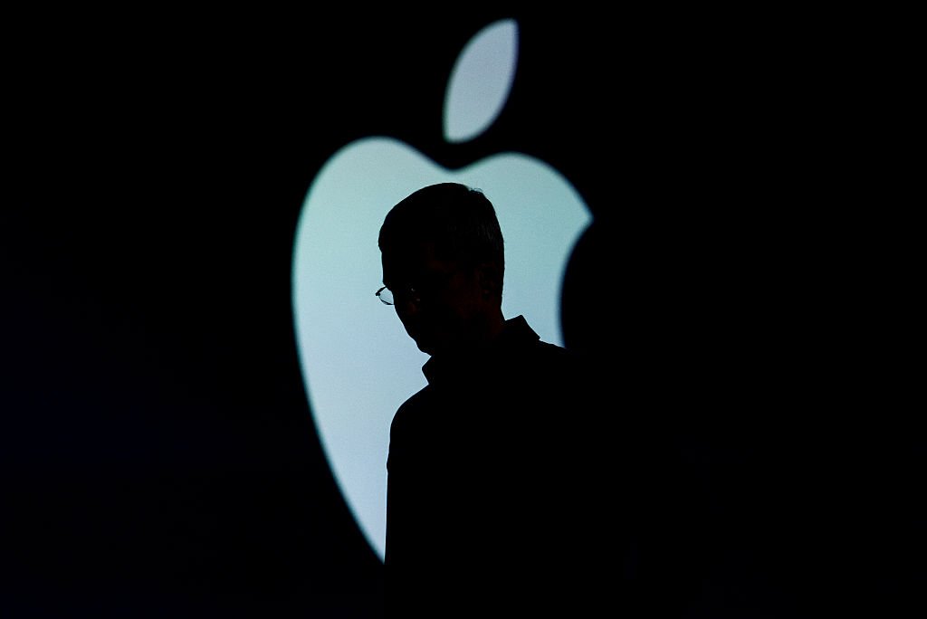 Silhueta do CEO da Apple, Tim Cook, junto da logo da Apple (Bloomberg/Getty Images)