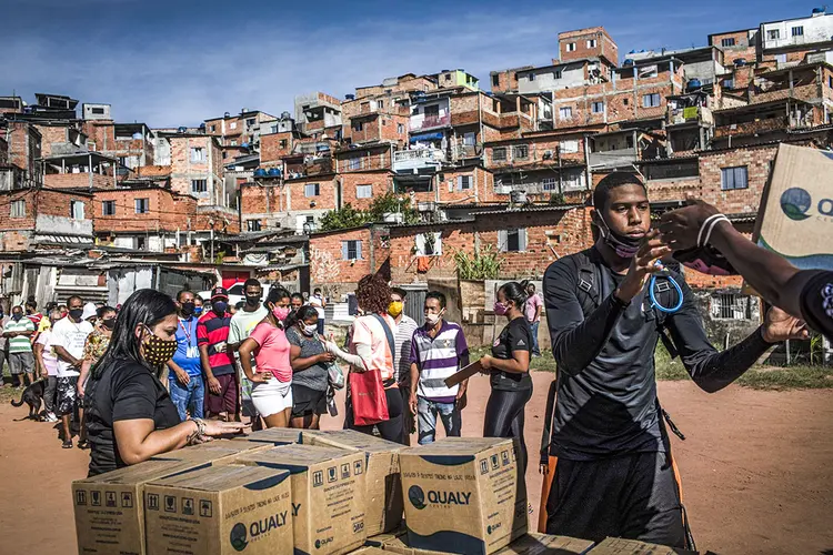 Voluntários distribuem caixas de alimentos e materiais de higiene a moradores da favela Vale das Virtudes, em São Paulo, em 12 de junho de 2020. (Victor Moriyama/Bloomberg)