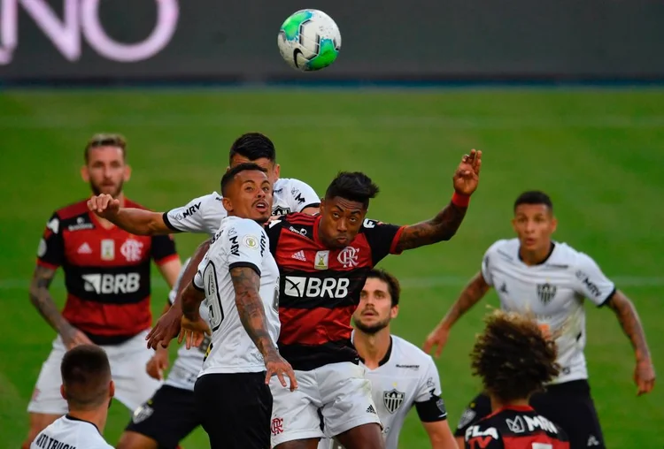 Flamengo's Bruno Henrique (C, right) vies for the ball with Atletico Mineiro's Allan (C, left) as Flamengo's Uruguayan Giorgian De Arrascaeta runs from behind during their first round match of the Brazilian Football Championship at the Maracana stadium in Rio de Janeiro, Brazil, on August 9, 2020. - The match is played behind closed doors as a measure to combat the spread of the novel coronavirus COVID-19. (Photo by Mauro PIMENTEL / AFP) (Photo by MAURO PIMENTEL/AFP via Getty Images) (MAURO PIMENTEL / Colaborador/Getty Images)