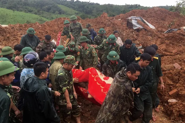 Militares carregam vítimas de um deslizamento de terra no Vietnã (STR / Vietnam News Agency/AFP)