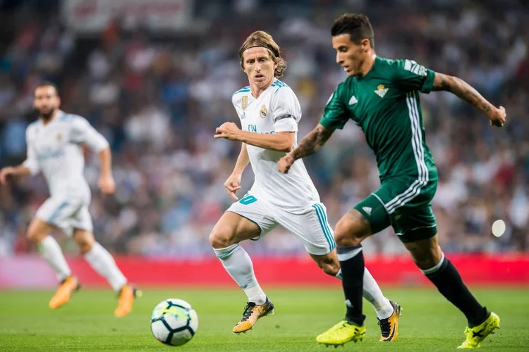 Lucas Modric, do Real Madri, e Cristian Tello Herrera, do Real Betis, disputam a bola em partida da LaLiga: clube quer ser o mais sustentável do mundo (Power Sport Images / Colaborador/Getty Images)