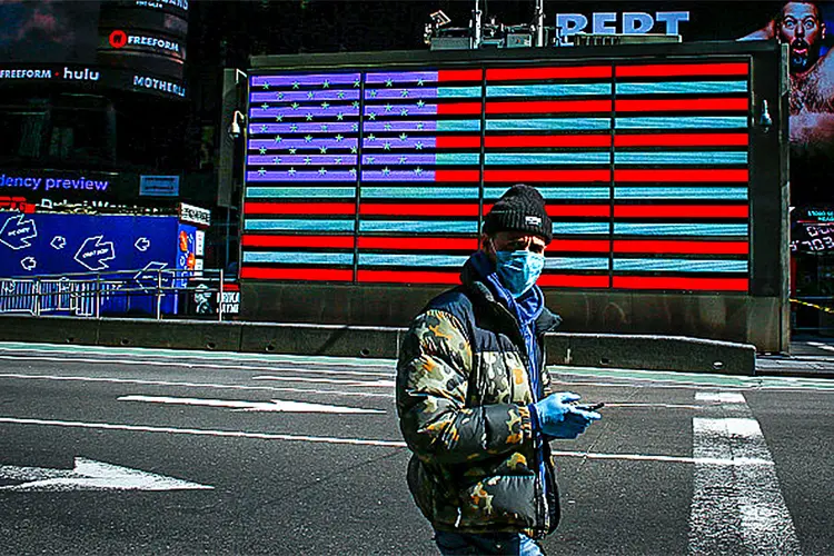 A man wears a face mask as he check his phone in Times Square on March 22, 2020 in New York City. - Coronavirus deaths soared across the United States and Europe on despite heightened restrictions as hospitals scrambled to find ventilators. (Photo by Kena Betancur / AFP) (Photo by KENA BETANCUR/AFP via Getty Images) (KENA BETANCUR/AFP via/Getty Images)