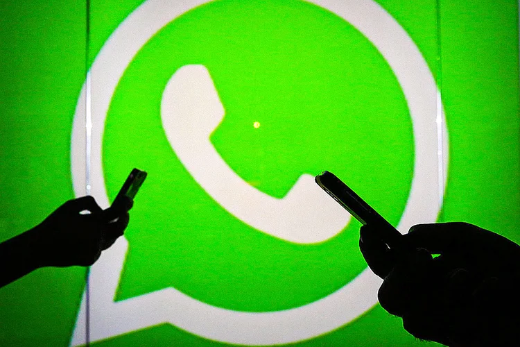 People are seen as silhouettes as they check mobile devices whilst standing against an illuminated wall bearing WhatsApp Inc's logo in this arranged photograph in London, U.K., on Tuesday, Jan. 5, 2016. WhatsApp Inc. offers a cross-platform mobile messaging application that allows users to exchange messages. Photographer: Chris Ratcliffe/Bloomberg via Getty Images (Bloomberg/Getty Images)