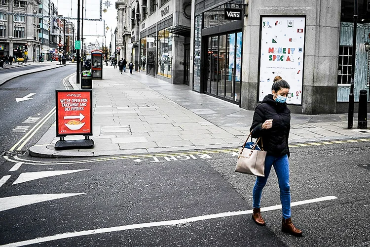 Pedestre com máscara caminha pela Oxfort Street deserta em Londres, 26 de novembro de 2020 (AFP/AFP)