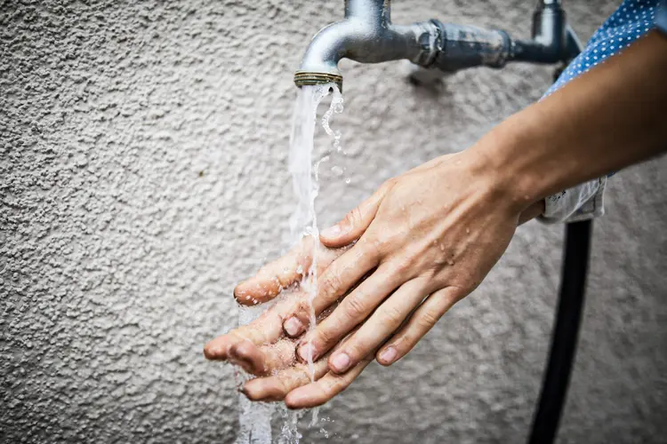 Cropped image of woman washing hands under faucet against wall (Luis Alvarez/Getty Images)