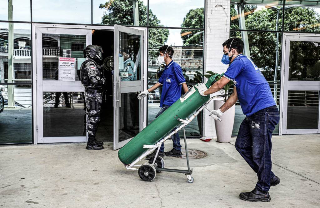 Trabalhador chega com cilindro de oxigênio ao hospital  (Bruno Kelly/Reuters)