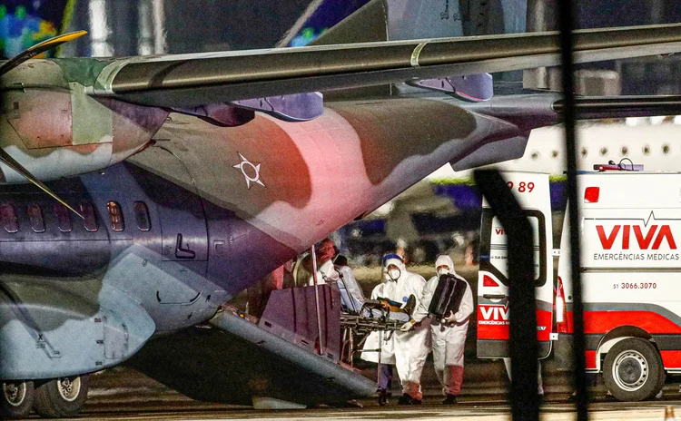 Trabalhadores da área de saúde transportam paciente com COVID-19 de avião da Força Aérea Brasileira após chegada de Porto Velho, estado de Rondônia, em meio ao surto da doença coronavírus (COVID-19), no aeroporto internacional Salgado Filho, em Porto Alegre, Brasil, em 27 de janeiro de 2021. 
 (Diego Vara/Reuters)