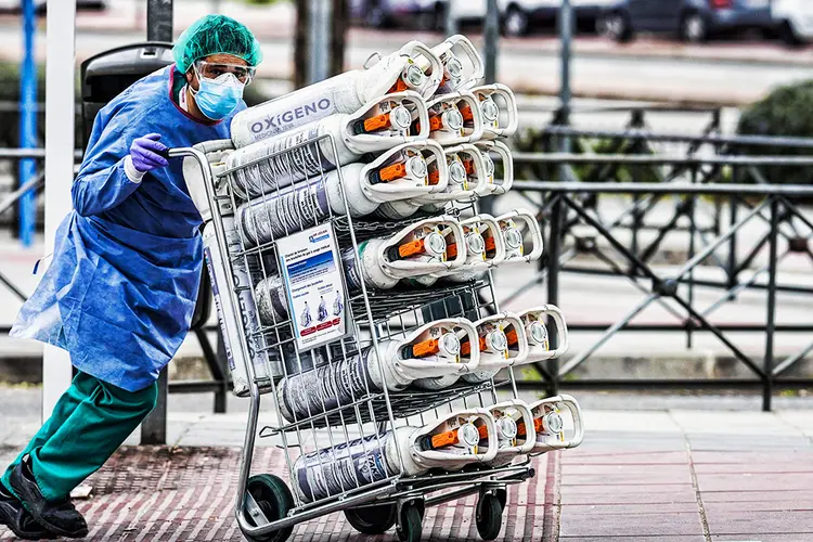 Trabalhador da saúde leva tanques de oxigênio à emergência de hospital. (Paul Hanna/Bloomberg)