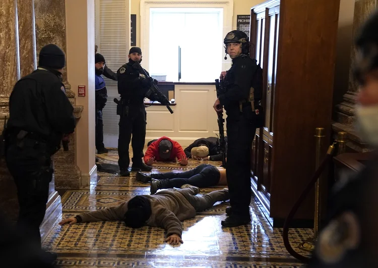 A polícia do Capitólio detém manifestantes do lado de fora da Câmara da Câmara durante uma sessão conjunta do Congresso em 6 de janeiro de 2021 em Washington, DC. O Congresso realizou uma sessão conjunta hoje para ratificar a vitória do Colégio Eleitoral 306-232 do presidente eleito Joe Biden sobre o presidente Donald Trump. Um grupo de senadores republicanos disse que rejeitaria os votos do Colégio Eleitoral de vários estados, a menos que o Congresso indicasse uma comissão para auditar os resultados das eleições (Drew Angerer/Getty Images)