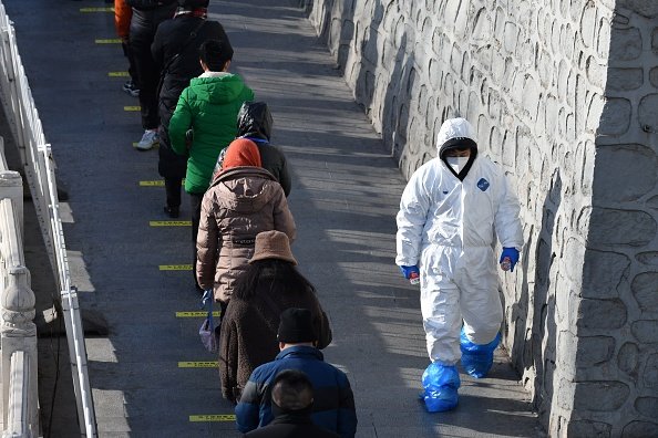 Profissional de saúde passa por moradores de Pequim: parte da cidade entrou em lockdown nesta segunda, dia 11 (Getty Images/Greg Baker)
