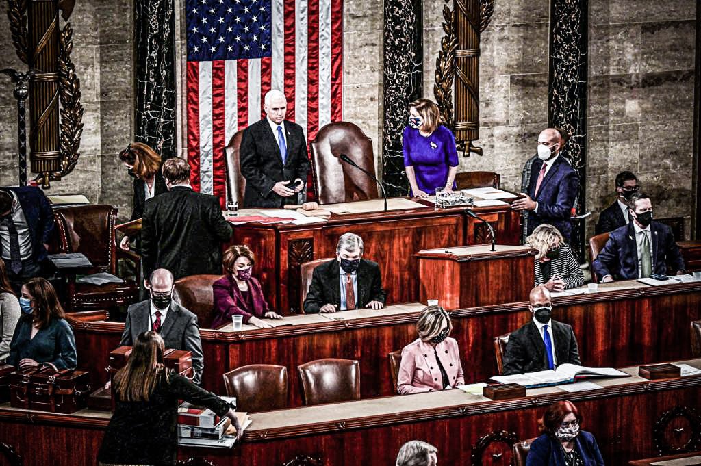 A presidente da Câmara dos EUA, Nancy Pelosi, ouve o vice-presidente dos EUA, Mike Pence, falar durante uma sessão conjunta do Congresso para certificar os resultados das eleições de 2020 no Capitólio em Washington, EUA, 6 de janeiro de 2021.  (Erin Scott/Reuters)