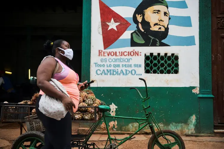 Mulher usa máscara em frente de propaganda do governo de Cuba (YAMIL LAGE/AFP/Getty Images)