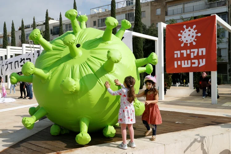 Crianças empurram um balão inflável representando o coronavírus em Tel Aviv. (AGENCE FRANCE-PRESSE/Reprodução)