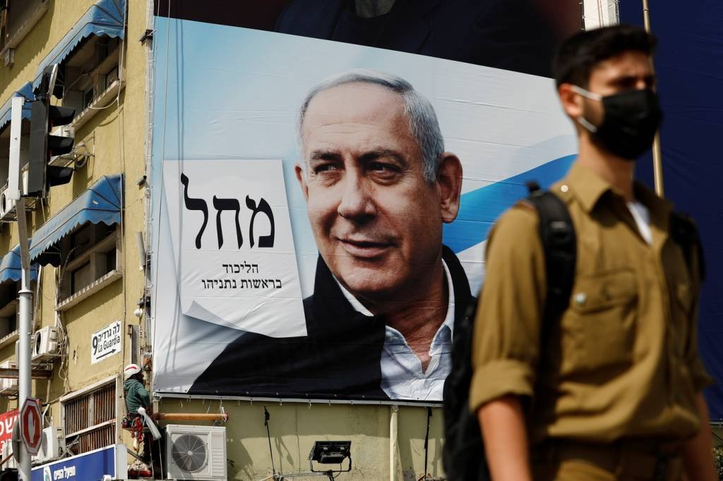 Soldado em frente a cartaz de campanha de Netanyahu: Likud, partido do premiê, deve ter maioria, mas ainda insuficiente (Corinna Kern/Reuters)