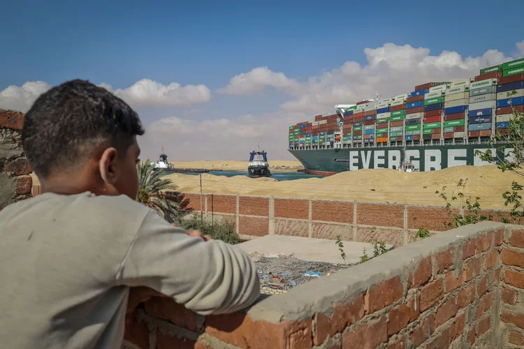 Menino observa Ever Given encalhado no Canal de Suez: navio bloqueou todo o transporte de mercadorias pelo estreito (Samuel Mohsen/picture alliance/Getty Images)