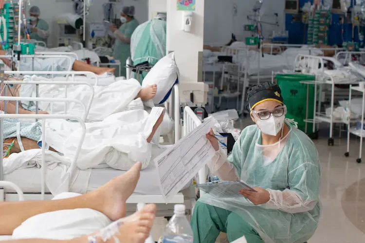 Trabalhadores de saúde tratam pacientes dentro de uma unidade de terapia intensiva (UTI) Covid-19 em um hospital de campanha na favela Heliópolis de São Paulo, Brasil, na sexta-feira, 19 de março de 2021.  (Bloomberg/Getty Images)