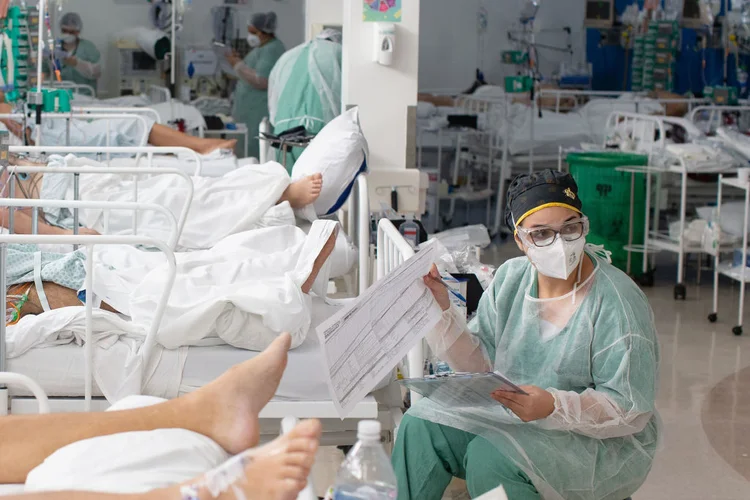 Trabalhadores de saúde tratam pacientes dentro de uma unidade de terapia intensiva (UTI) Covid-19 em um hospital de campanha na favela Heliópolis de São Paulo, Brasil, na sexta-feira, 19 de março de 2021.  (Bloomberg/Getty Images)