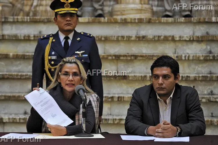 Jeanine Áñez, e, exercício da presidência interina da Bolívia, exibe um documento junto ao ministro da Justiça, Álvaro Coimbra, no palácio presidencial Quemado, em La Paz, em 20 de novembro de 2019 (AFP/AFP)