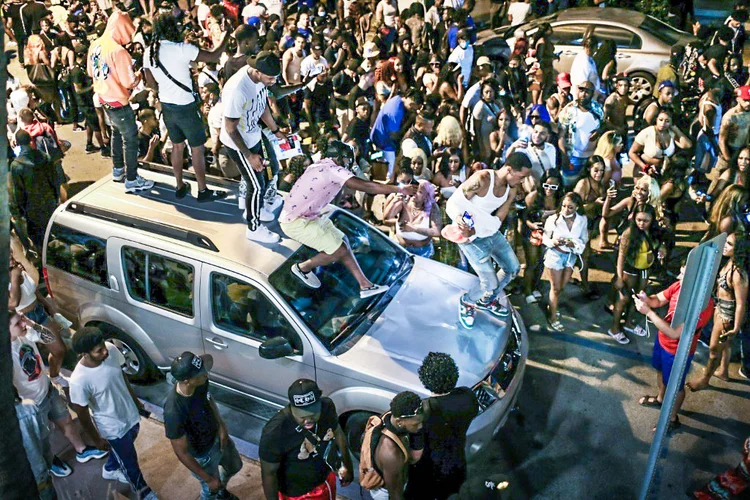Grupo de jovens dança no teto de carros em Miami Beach, quando entra em vigor um toque de recolher para conter a multidão de turistas. (AFP/AFP Photo)