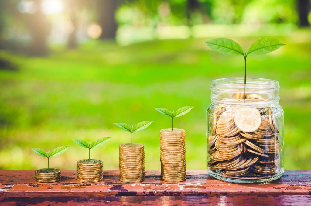 coins stack on wood table with green plant growing on. money saving business finance success wealth investment budget concept. startup plan. ESG. (Getty Images/Getty Images)
