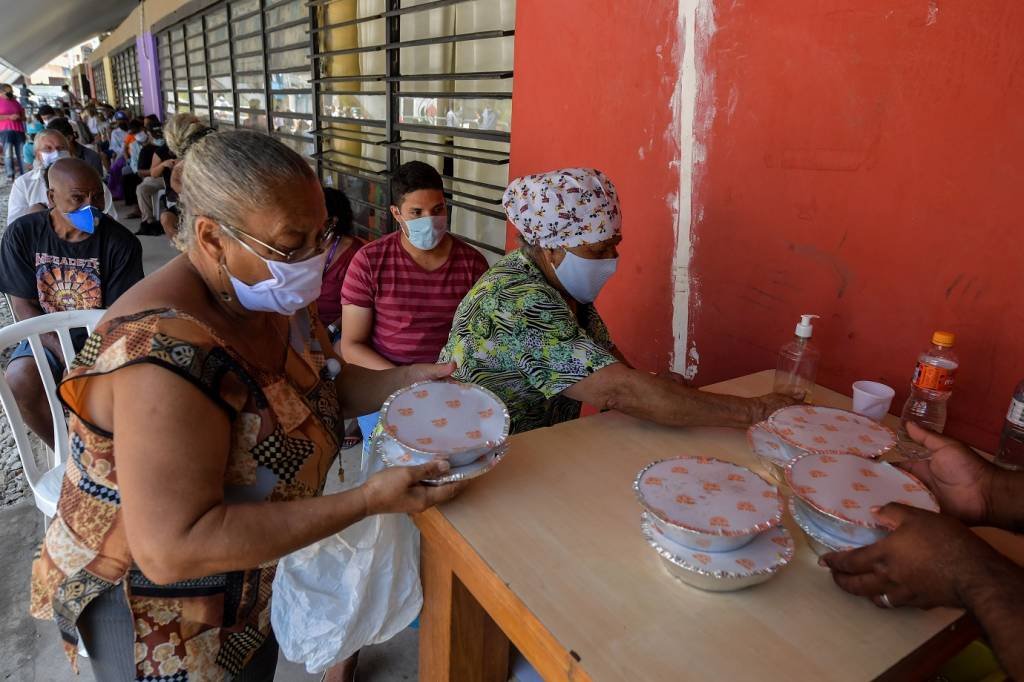 Moradores recebem refeições em um refeitório da favela Paraisópolis, em São Paulo, Brasil, em 28 de janeiro de 2021. - O pedágio econômico da pandemia do coronavírus atingiu especialmente as favelas brasileiras, mas as 10 maiores favelas do país (NELSON ALMEIDA/AFP/Getty Images)