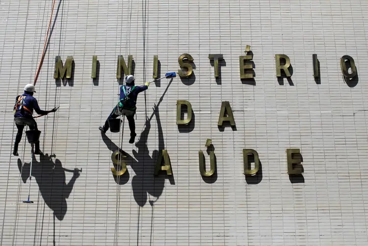 Funcionários limpam fachada do prédio do Ministério da Saúde. (Ueslei Marcelino/Reuters)