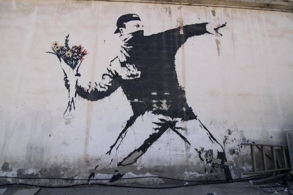Famoso mural de Bansky com o desenho da obra  'Love Is In The Air', em muro na Palestina (MATTHIAS KESTLE / ALAMY STOCK PHOTO / BANKSY/Divulgação)
