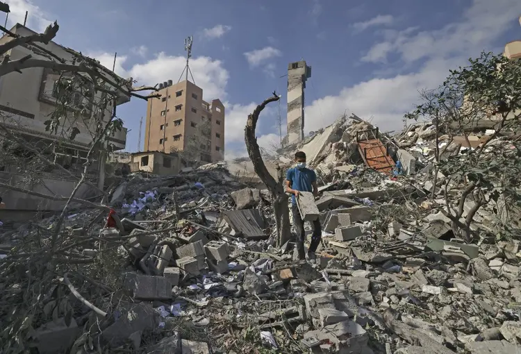 Conflito Israel-Gaza: jovem palestino procura itens recuperáveis ​​em meio aos escombros do prédio Kuhail, que foi destruído em um ataque aéreo israelense na cidade de Gaza em 18 de maio de 2021. (MAHMUD HAMS/AFP)