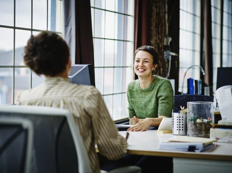 Smiling female business owners in discussion at workstation in office (Getty Images/Getty Images)