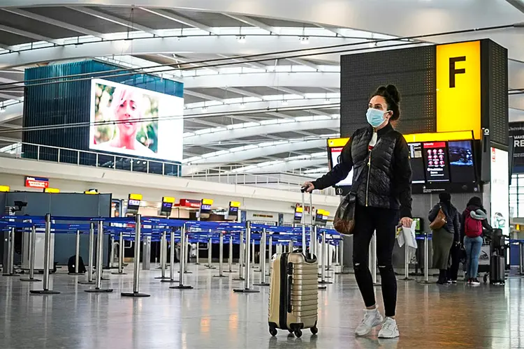 Mulher com máscara caminha pelo aeroporto de Heathrow, em Londres (AFP/AFP)