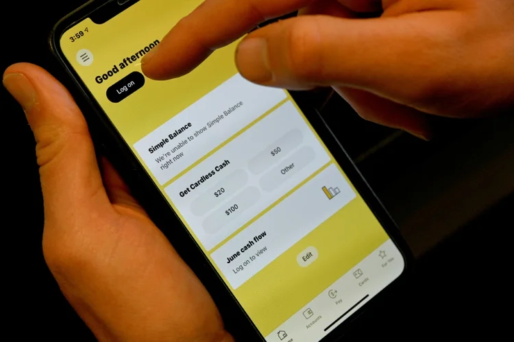 Homem tenta se conectar a sua conta bancária pelo celular, em Sydney, em meio a uma pane nos serviços on-line de várias empresas na Austrália, em 17 de junho de 2021 (AFP/AFP)